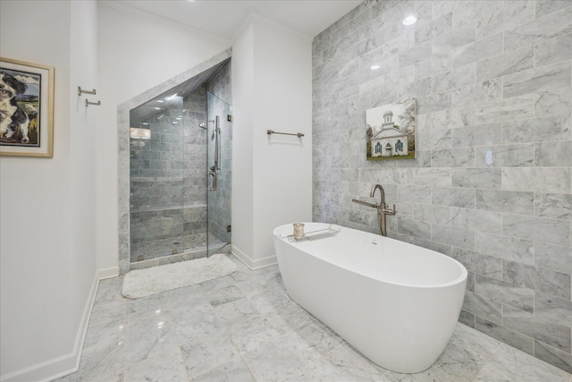 bathroom with tile walls, baseboards, marble finish floor, a soaking tub, and a stall shower