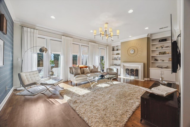 living area with ornamental molding, a fireplace with flush hearth, dark wood finished floors, and a notable chandelier