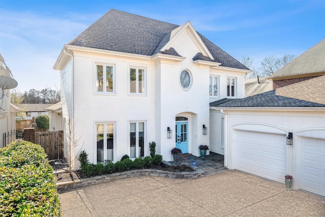 french country inspired facade featuring brick siding, a shingled roof, and fence