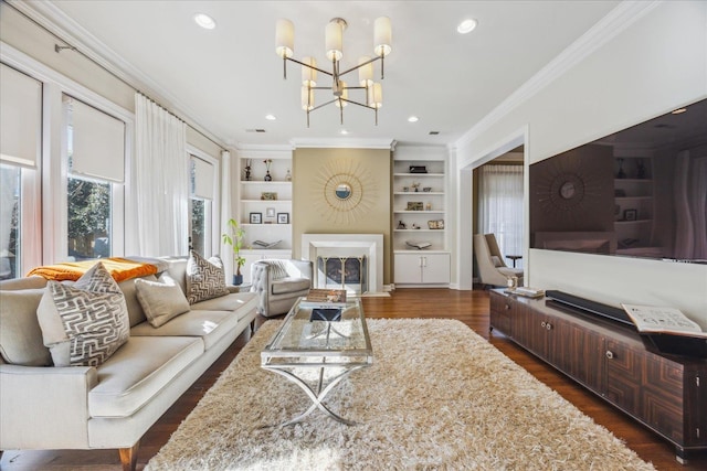 living room with built in features, dark wood finished floors, a fireplace, crown molding, and recessed lighting