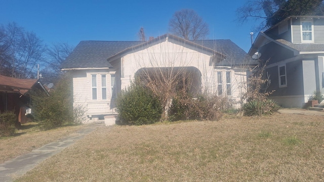 view of front of property featuring a front lawn and a shingled roof