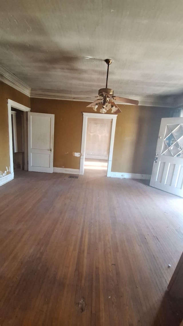 unfurnished living room with ornamental molding, a ceiling fan, baseboards, and wood finished floors