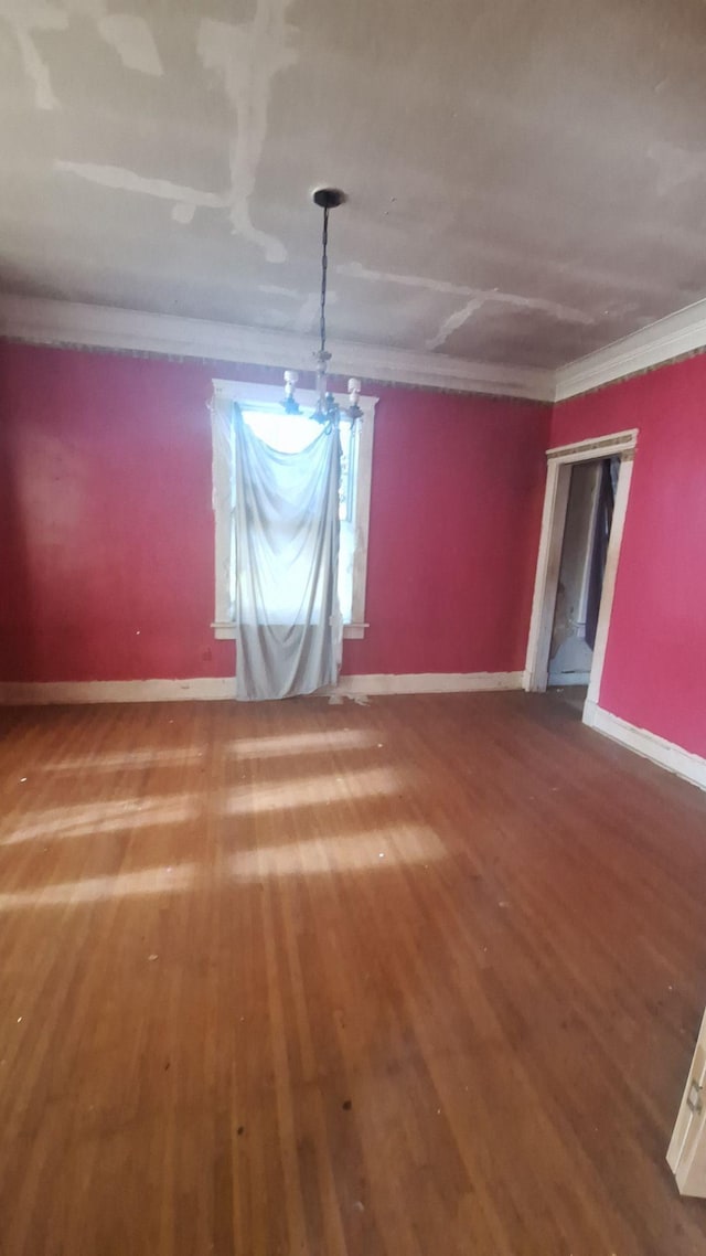 unfurnished dining area featuring baseboards, crown molding, and wood finished floors