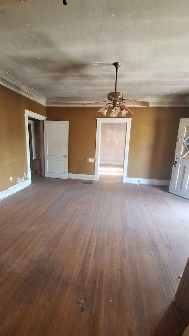 unfurnished living room featuring wood-type flooring, visible vents, ornamental molding, and baseboards