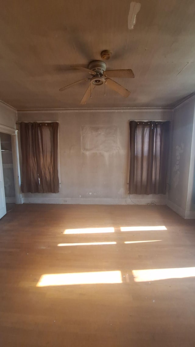 empty room featuring a ceiling fan, ornamental molding, and wood finished floors