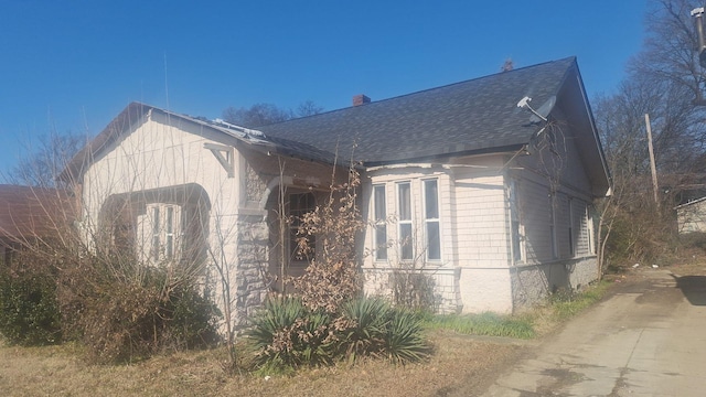 view of property exterior featuring a shingled roof and a chimney