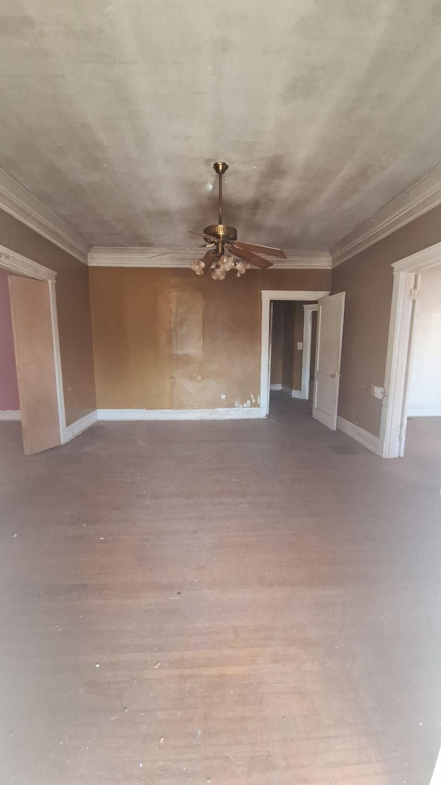 spare room featuring ornamental molding, wood finished floors, a ceiling fan, and baseboards