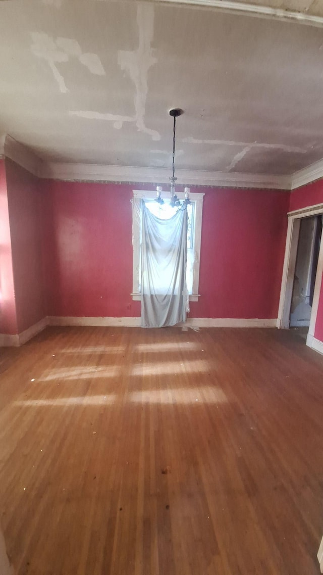 unfurnished dining area featuring crown molding, baseboards, and wood finished floors