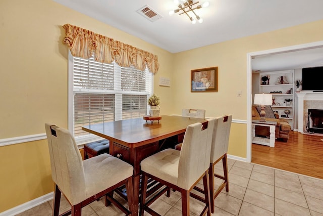 dining room featuring light tile patterned floors, visible vents, baseboards, and a tiled fireplace