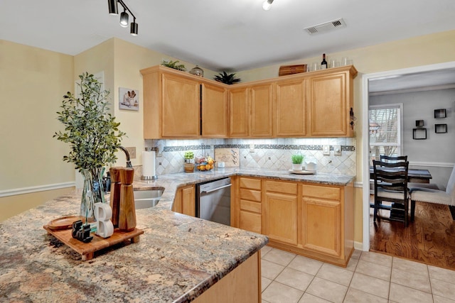 kitchen with stainless steel dishwasher, light stone counters, visible vents, and backsplash