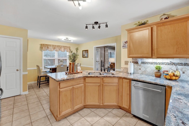 kitchen featuring dishwasher, a peninsula, light tile patterned flooring, and a sink