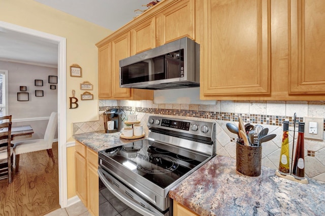 kitchen with backsplash, light stone countertops, light brown cabinetry, light tile patterned floors, and appliances with stainless steel finishes