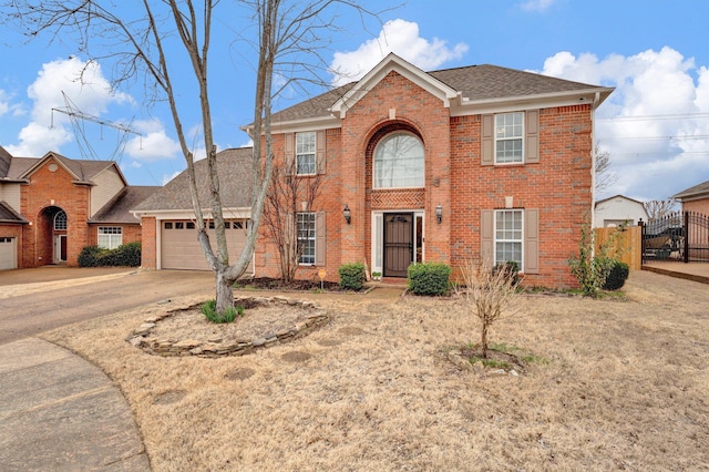 colonial house featuring concrete driveway, an attached garage, fence, and brick siding