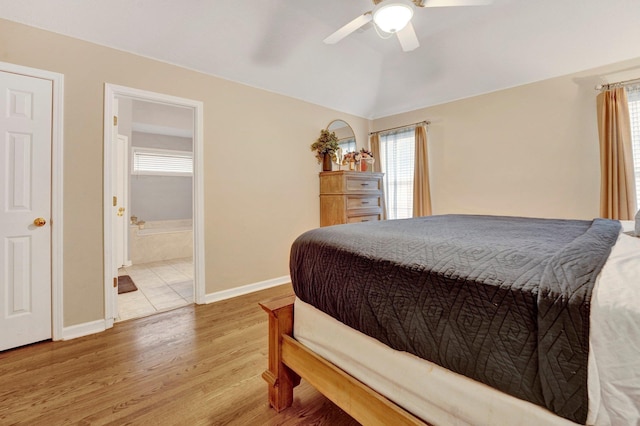 bedroom with ceiling fan, baseboards, vaulted ceiling, light wood-style flooring, and ensuite bathroom