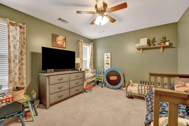 bedroom featuring visible vents, light colored carpet, and a ceiling fan