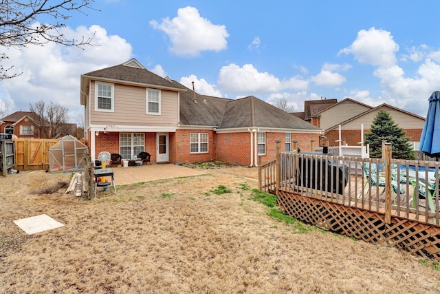 rear view of house with brick siding, an exterior structure, an outdoor structure, and fence