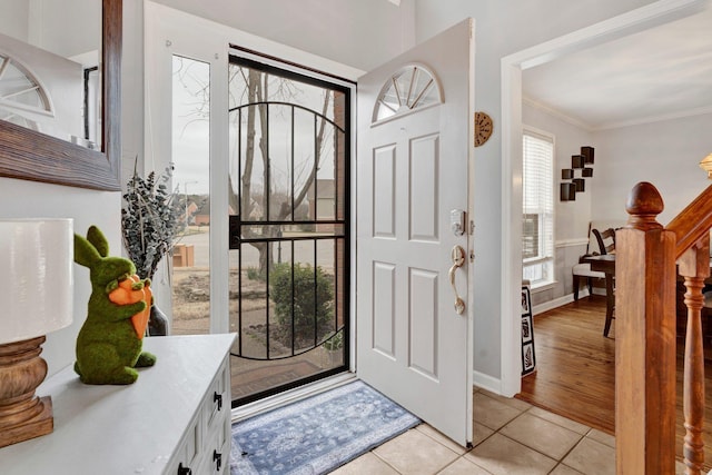 foyer featuring stairs, baseboards, light tile patterned flooring, and crown molding