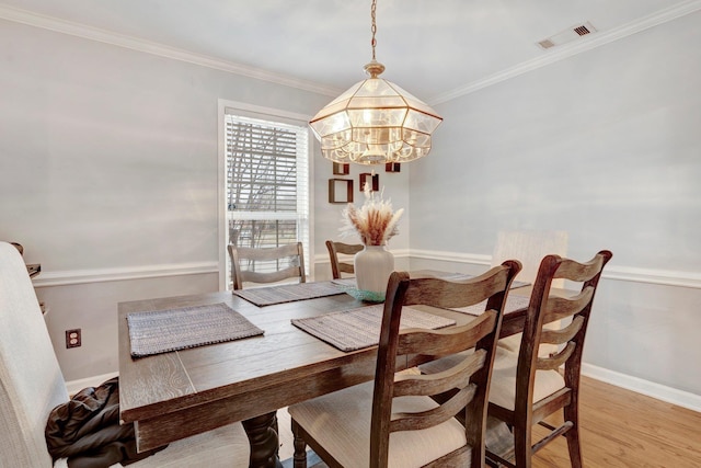 dining area featuring visible vents, crown molding, baseboards, a chandelier, and light wood-style flooring