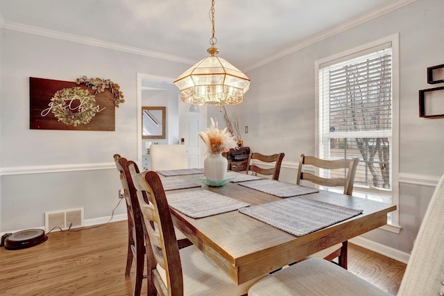 dining room with visible vents, baseboards, light wood-style flooring, and crown molding