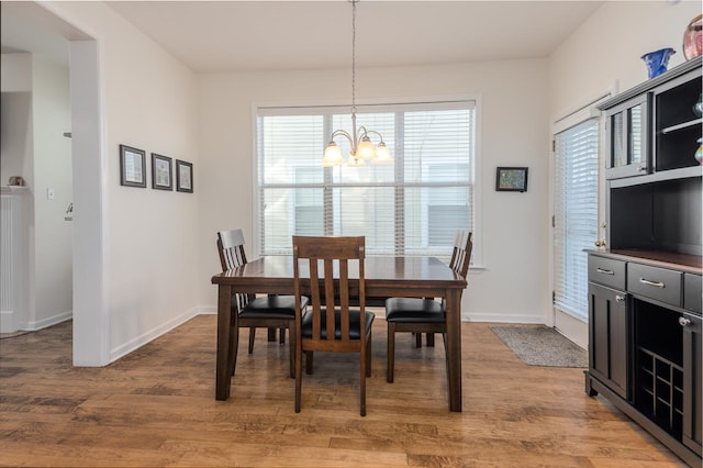 dining space featuring a notable chandelier, light wood-type flooring, baseboards, and a healthy amount of sunlight