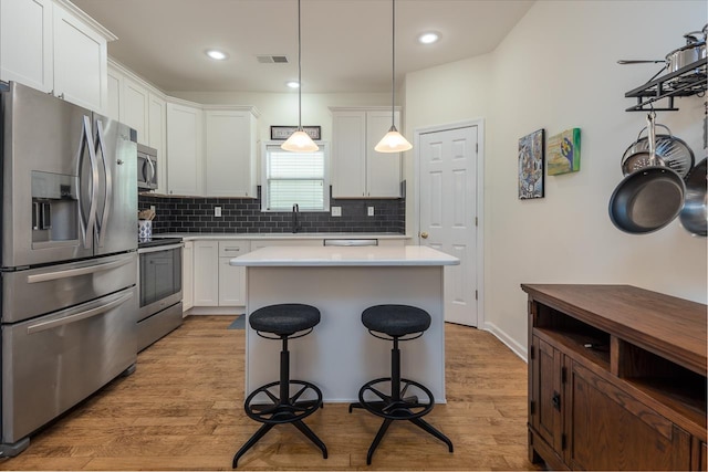 kitchen with stainless steel appliances, tasteful backsplash, light countertops, visible vents, and a sink