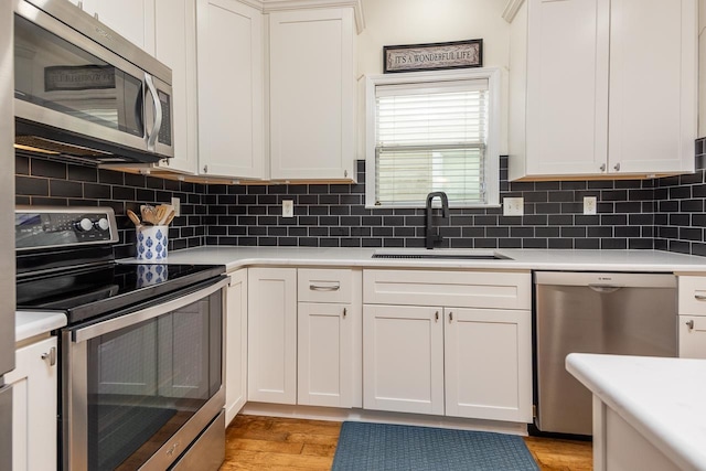 kitchen with appliances with stainless steel finishes, light countertops, a sink, and decorative backsplash