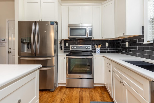 kitchen featuring light wood-type flooring, backsplash, stainless steel appliances, and light countertops