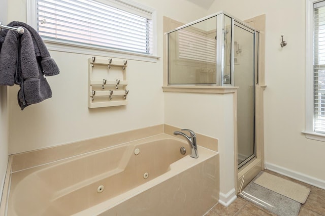 full bath featuring a tub with jets, a stall shower, a wealth of natural light, and tile patterned floors