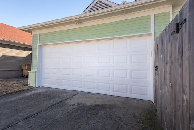 garage featuring driveway and fence