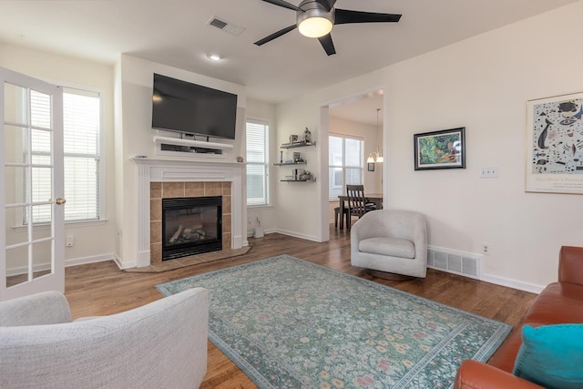 living room featuring visible vents, wood finished floors, and a tile fireplace