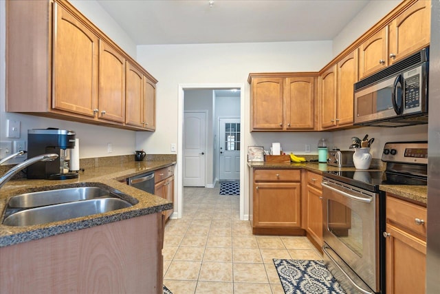 kitchen featuring stainless steel appliances, brown cabinetry, a sink, and light tile patterned floors