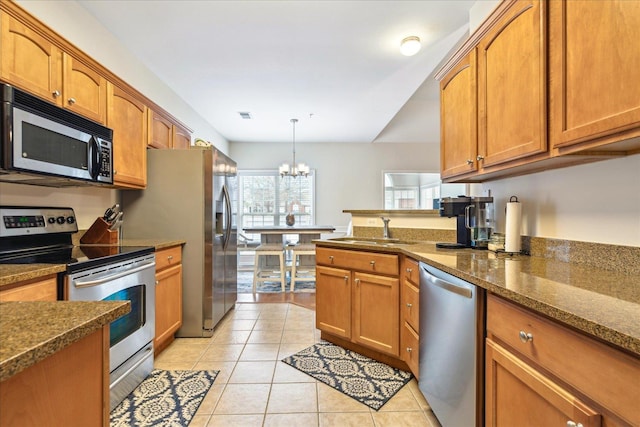 kitchen with light tile patterned flooring, stainless steel appliances, a sink, visible vents, and brown cabinetry