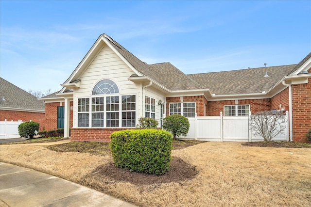 exterior space with roof with shingles, fence, and brick siding