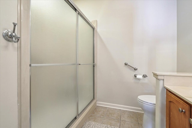 bathroom with toilet, a shower with shower door, vanity, baseboards, and tile patterned floors