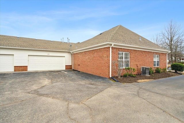 view of property exterior featuring brick siding, central AC unit, and roof with shingles