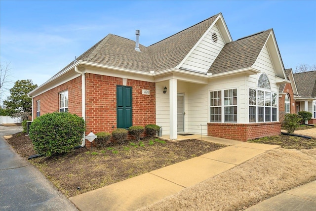 view of front facade with a shingled roof and brick siding