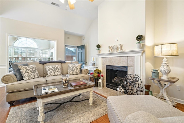 living room featuring a fireplace, wood finished floors, a ceiling fan, visible vents, and baseboards