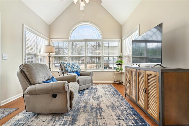 living area featuring high vaulted ceiling, wood finished floors, a ceiling fan, and baseboards