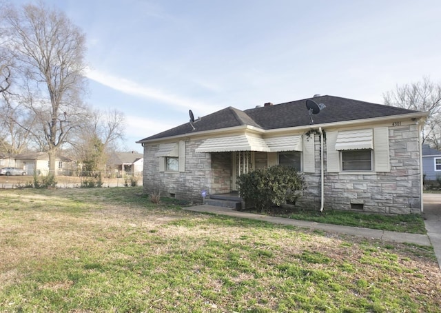 back of property with stone siding, roof with shingles, crawl space, fence, and a yard