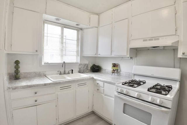 kitchen featuring white cabinets, white gas range, light countertops, under cabinet range hood, and a sink