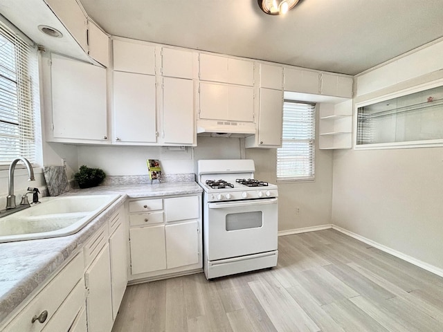 kitchen with under cabinet range hood, a sink, white cabinets, white range with gas cooktop, and light countertops