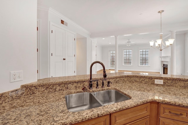 kitchen featuring open floor plan, a sink, light stone countertops, and crown molding