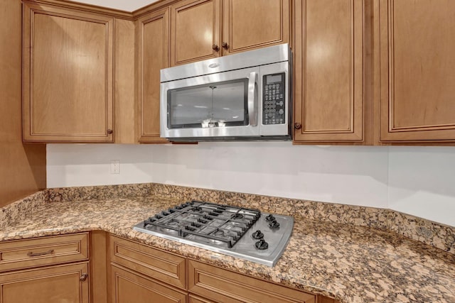 kitchen featuring brown cabinets, light stone counters, and stainless steel appliances