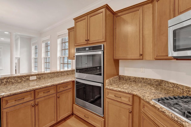 kitchen with ornamental molding, appliances with stainless steel finishes, brown cabinetry, and light stone counters