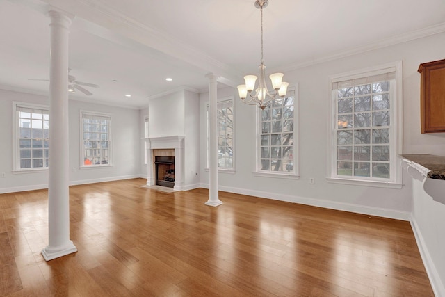 unfurnished living room featuring light wood finished floors, decorative columns, baseboards, a fireplace with flush hearth, and ornamental molding