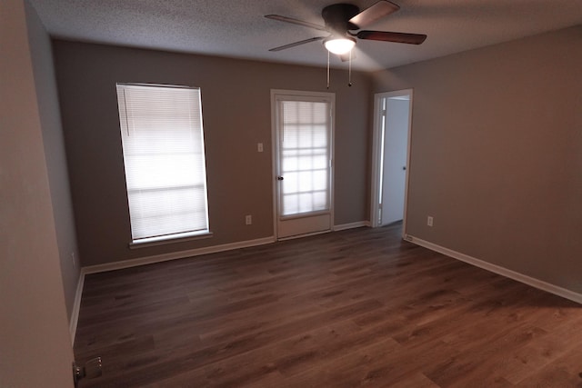 unfurnished room with a textured ceiling, dark wood-style flooring, a ceiling fan, and baseboards