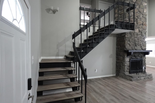 stairs with a fireplace, baseboards, and wood finished floors