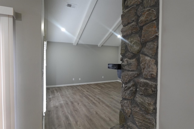 unfurnished living room with lofted ceiling, visible vents, baseboards, and wood finished floors