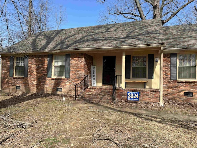 ranch-style house featuring roof with shingles, brick siding, and crawl space