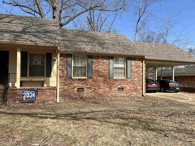 view of front of home featuring a shingled roof, crawl space, brick siding, and a carport